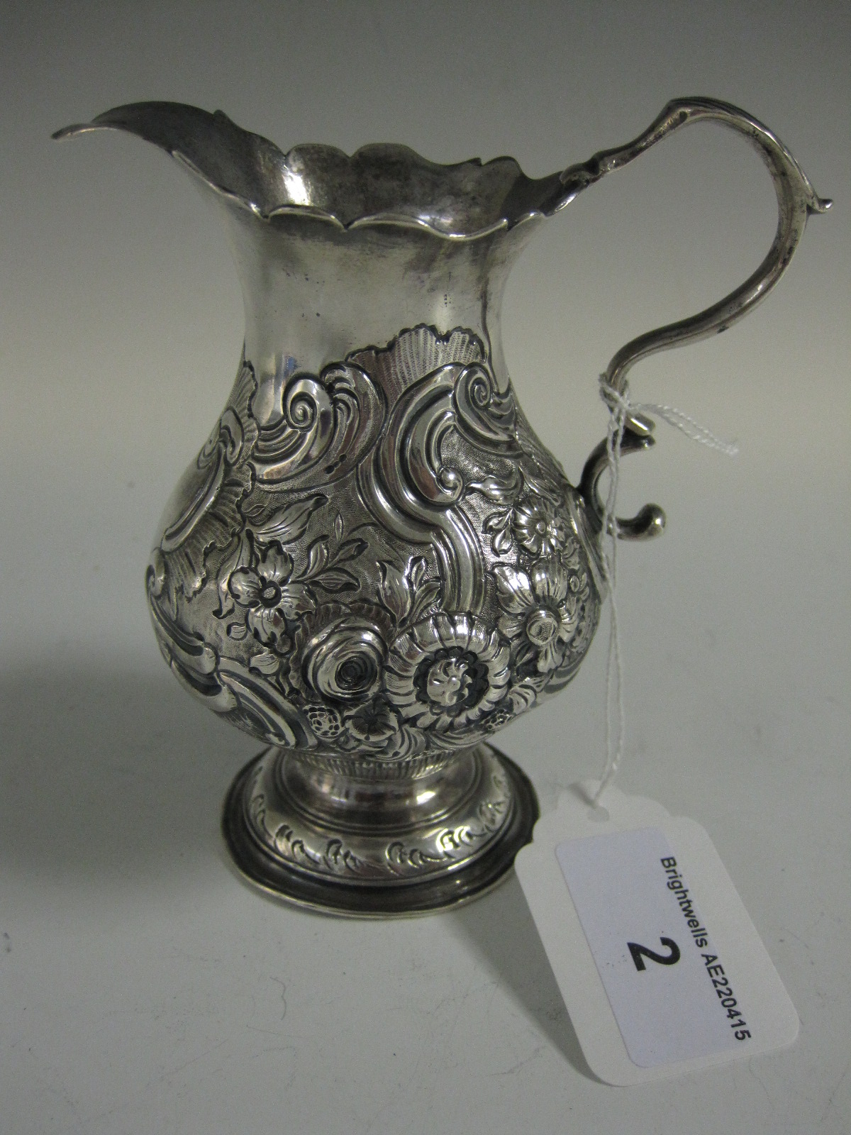 A George II baluster silver Cream Jug with scroll handle, later embossed scroll and floral