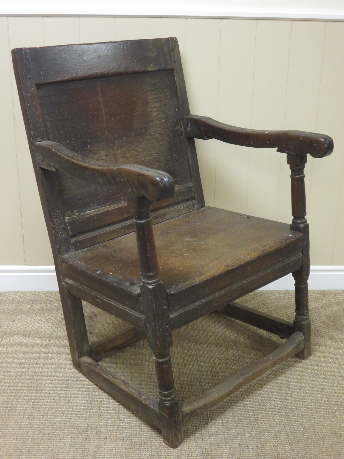 A 17th Century oak Wainscot Armchair with panelled back on turned front supports and squared