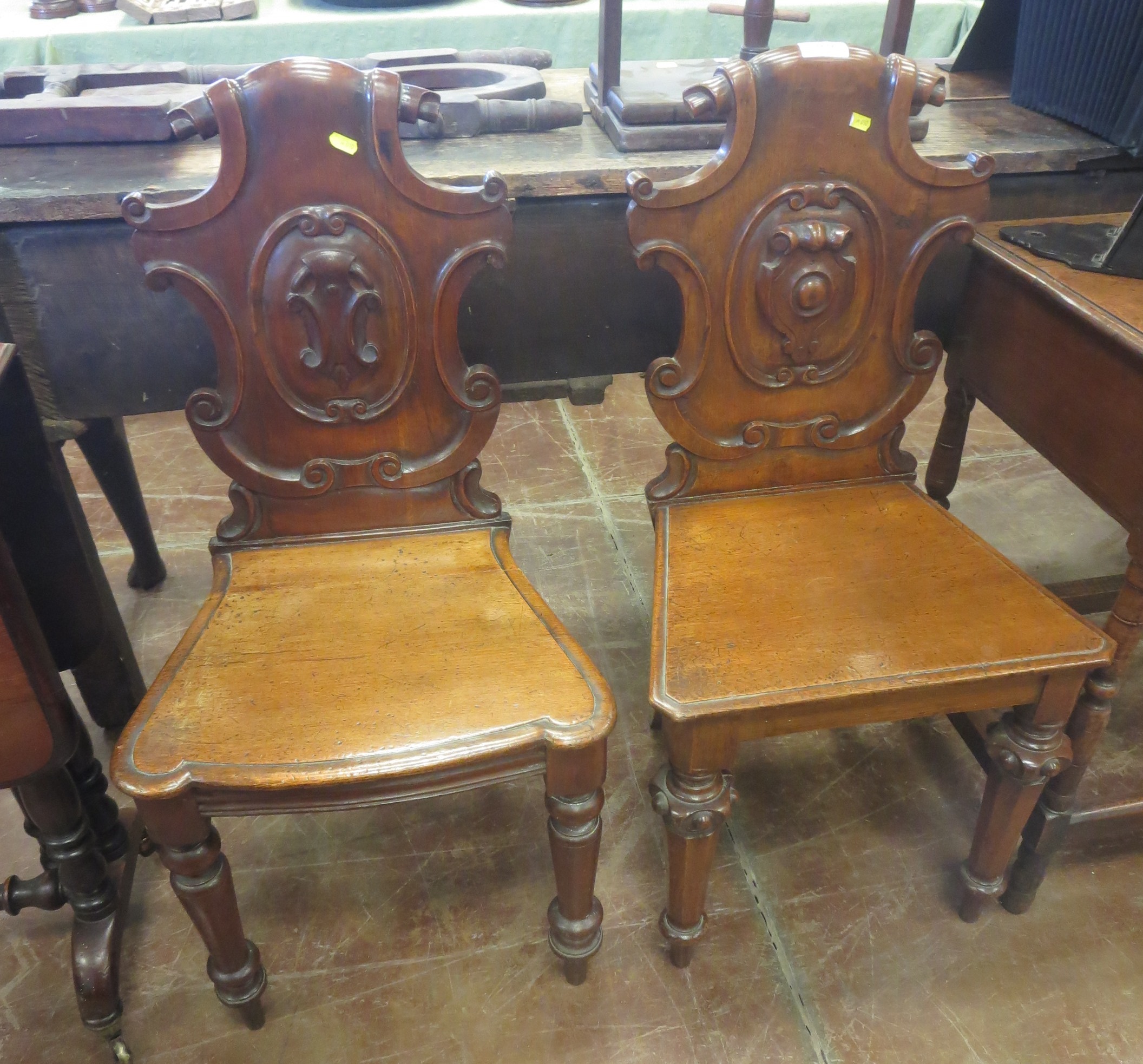 A matched pair of mahogany Victorian Hall Chairs with carved shaped backs, one on octagonal shaped