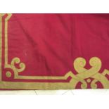 A pair of crimson baize Curtains with an appliqued gold scrolled design to lower edge and sides.