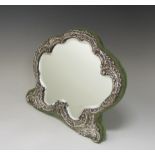 A Victorian silver framed Easel Mirror, the shaped plate with scrolled embossed frame on green