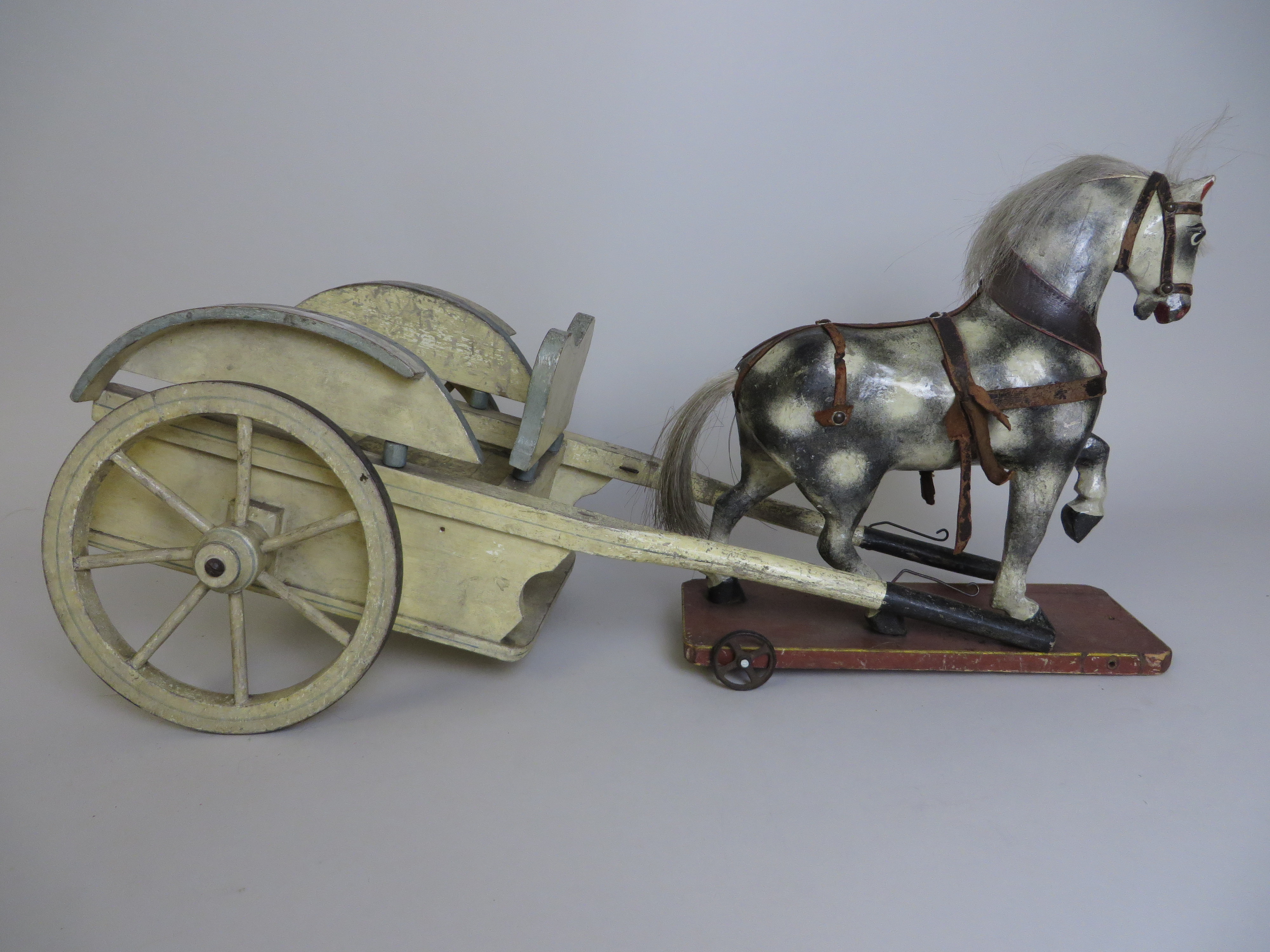 A dappled carved wooden Horse on wheels with matching cream and blue painted Cart. 19th Century.