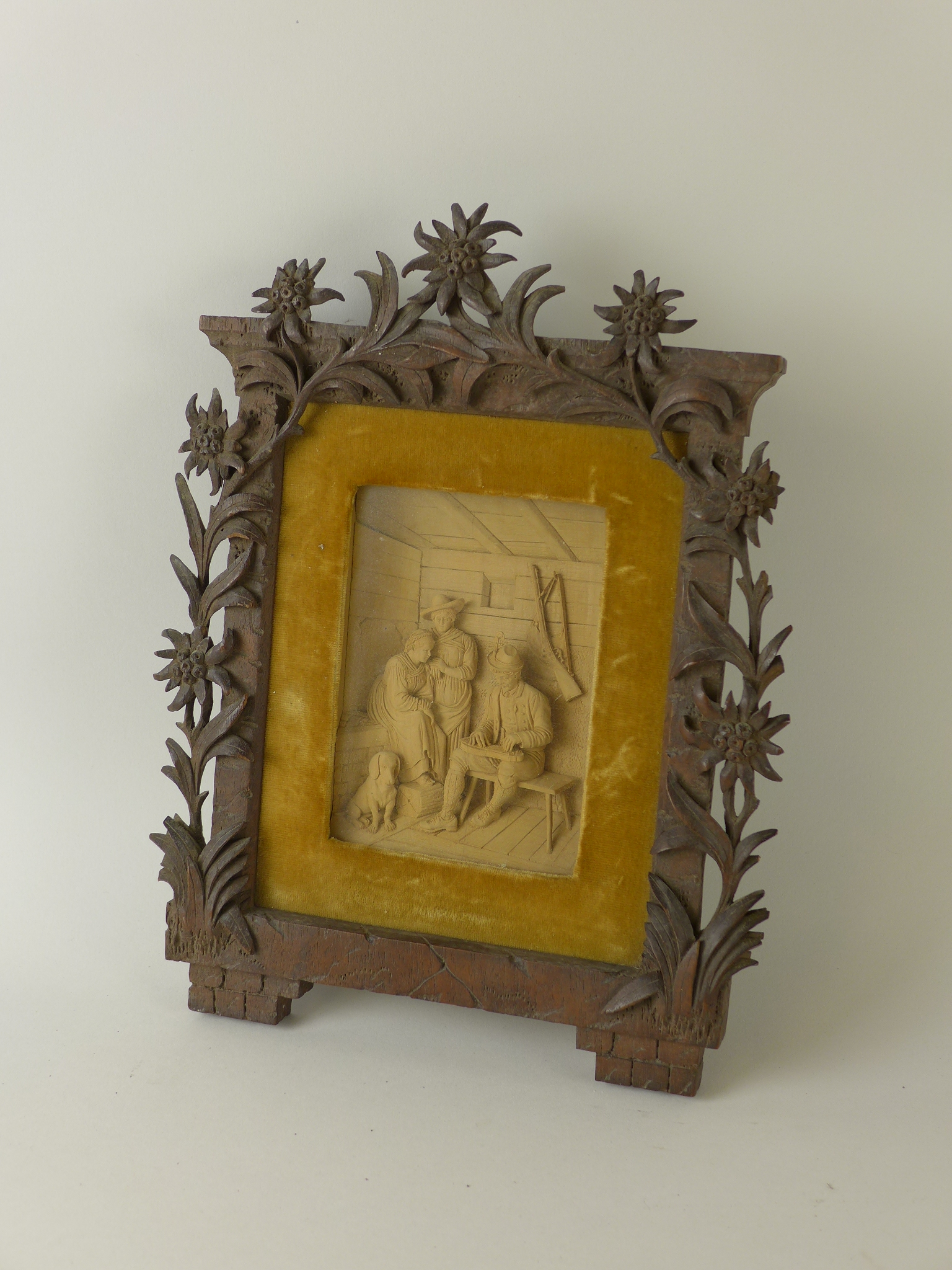 A German carved Frame containing an interior relief figure group of a man playing a musical