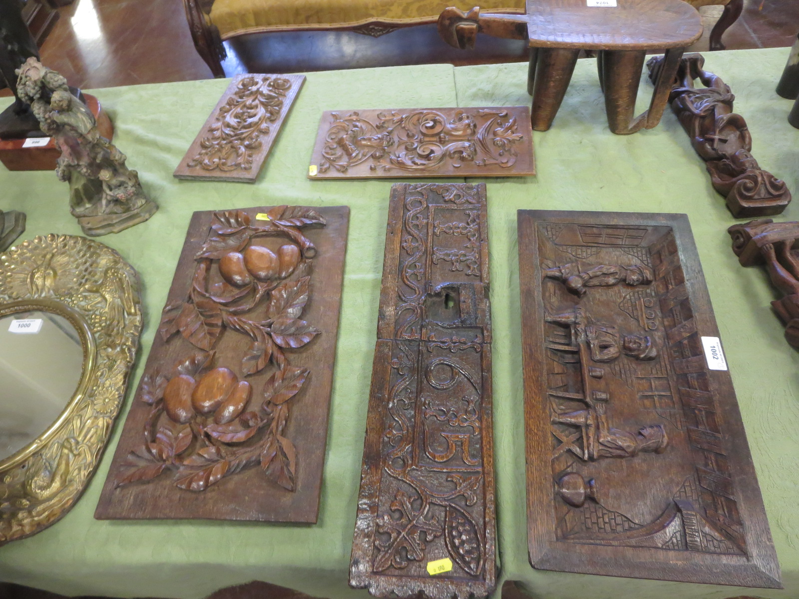 A collection of five carved Panels including figures in an Inn, foliate scrolls, fruit etc