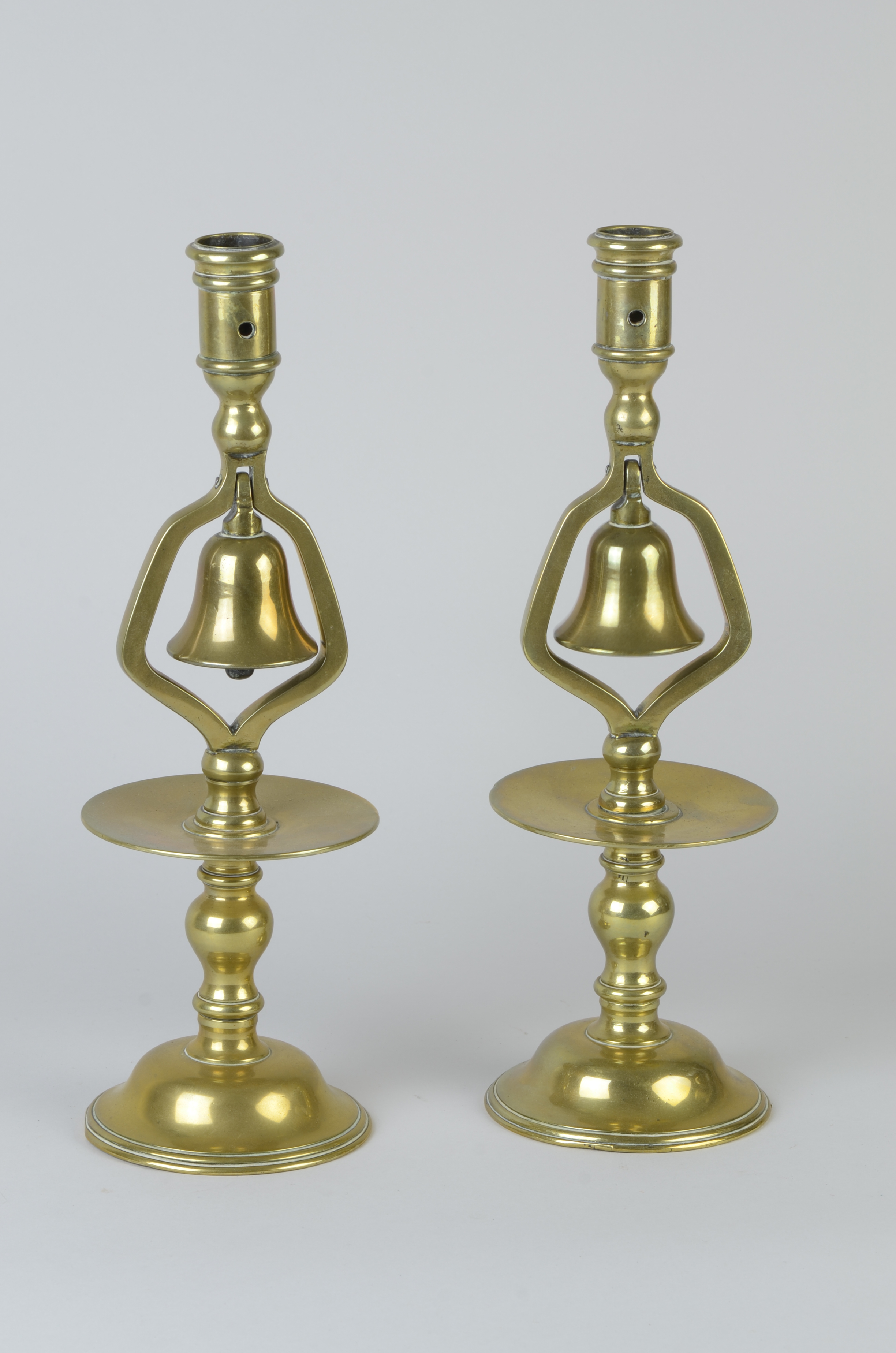 A pair of Victorian brass Tavern Sticks mounted with bells with broad drip pans and circular