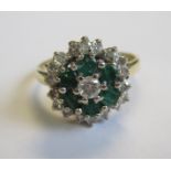 A Diamond and Emerald cluster Ring claw-set brilliant-cut diamond within frame of six emeralds and