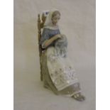 A Lladro figure of a lady sewing whilst