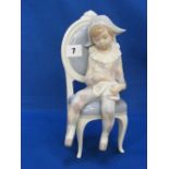 A Lladro figure of a boy harlequin seate