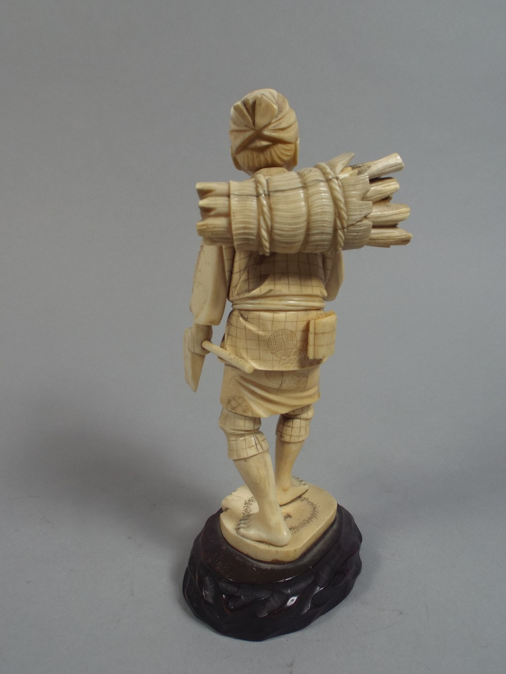 An Early 20th Century Ivory Okimono Figure of an Elderly Wood Cutter Holding an Axe and Pipe. - Image 2 of 2