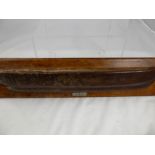 A wall mounted item in the form of a ship's hull, the teak being from HMS Champion, built by