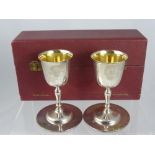 A Solid Silver Twin Goblet Set, the goblets having gilded interior with matching coasters,