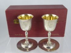 A Solid Silver Twin Goblet Set, the goblets having gilded interior with matching coasters,