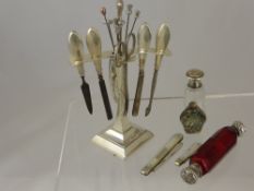 A silver manicure set on stand together with hat pin, red double ended scent bottle with silver lid,