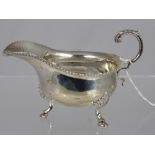 A Solid Silver Sauce Boat, the boat having a ribboned edge on hoof feet. Birmingham hallmarked dated