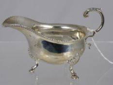 A Solid Silver Sauce Boat, the boat having a ribboned edge on hoof feet. Birmingham hallmarked dated