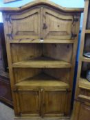 A Mexican pine corner unit having an arched top with cupboard immediately below, with open shelves