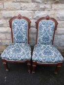 A pair of decorative oak hall chairs upholstered with a green leaf style damask.