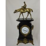 A Victorian style slate mantle clock on scroll feet with a brass figure of a jockey on horseback