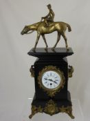 A Victorian style slate mantle clock on scroll feet with a brass figure of a jockey on horseback