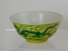 A yellow and green Chinese porcelain bowl painted with a leaping dragon among scrolling foliage