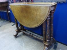 An Edwardian oval drop leaf occasional table, the top being walnut on a mahogany base with carved