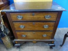 A small Edwardian chest of drawers on a raised base, inlaid on the top on edged surround, and having