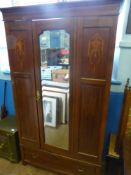 An Edwardian wardrobe having a bevelled glass mirror to the door, with inlaid panels and a drawer to