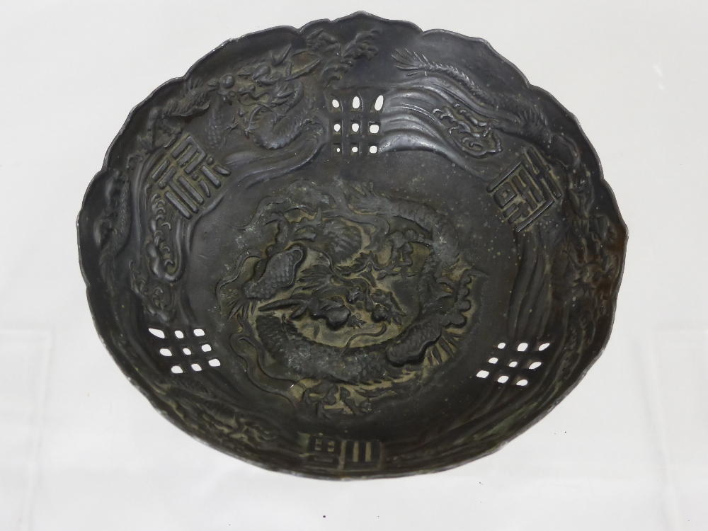 A Chinese silver metal bowl decorated with chasing dragons with character marks to side, est. 10 x