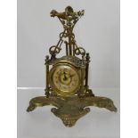 A Victorian brass hanging clock on a stand, the stand having shell shaped decoration on shell feet.