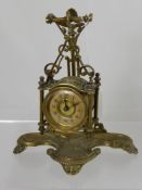 A Victorian brass hanging clock on a stand, the stand having shell shaped decoration on shell feet.