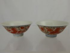 A pair of Chinese porcelain bowls depicting red phoenix in flight with chrysanthemum and scroll leaf