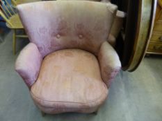 An antique tub chair upholstered in a pinkish fabric.