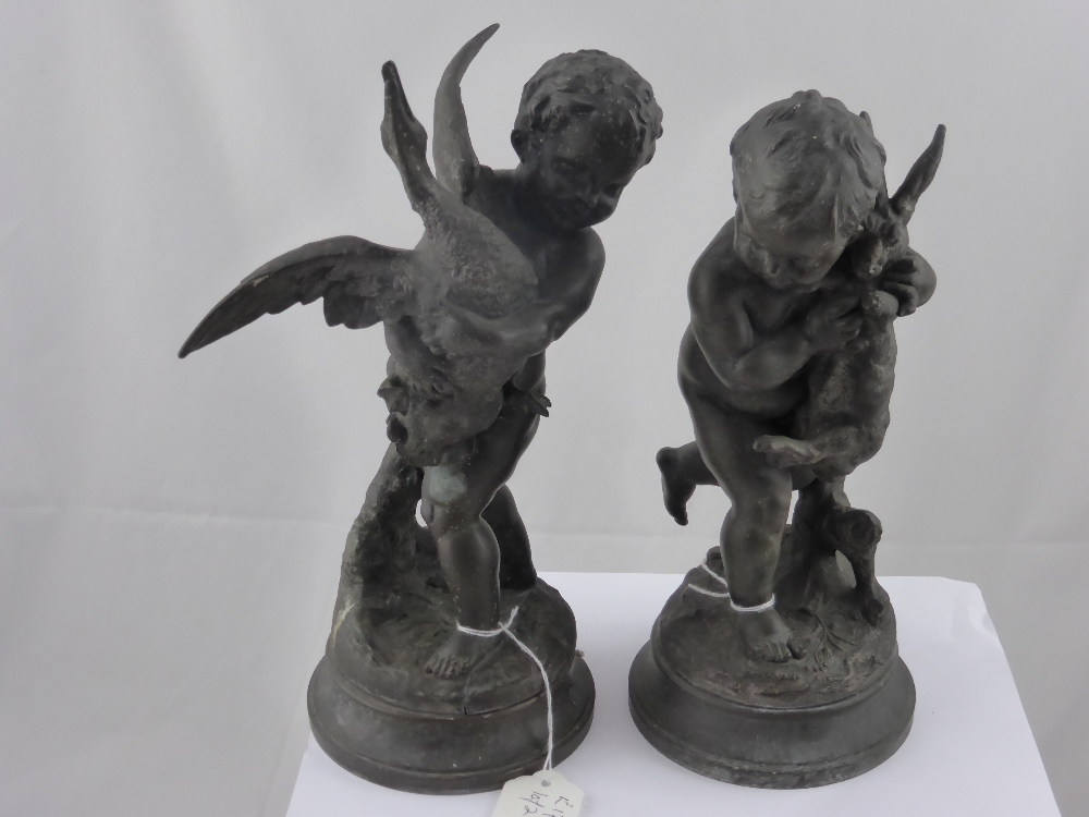 A pair of bronze effect cherubs, one holding a goose, the other a hare, approx. height 27 cms.