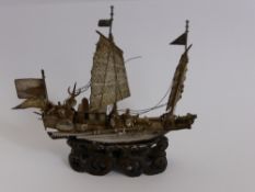 An Antique Silver Chinese Junk, supported on an openwork wooden stand, approx 11 cms