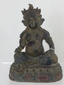 A bronzed figure of Buddha holding a rat in one hand and fruit in the other, the figure being on a