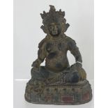 A bronzed figure of Buddha holding a rat in one hand and fruit in the other, the figure being on a