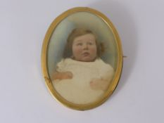 An Oval 18 ct Gold Frame with a photograph of a toddler.