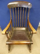 A Victorian oak rocking chair having bobbin decoration to the spindles and a leather seat.