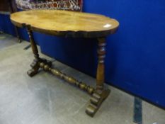 An oval mahogany coffee table having carved indentations to the top on turned legs and stretcher,