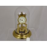 A Brass Pendulum Clock under a glass dome.