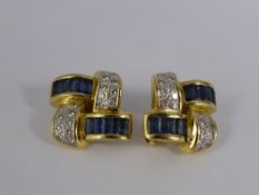 A Pair of 18 ct Yellow Gold Diamond and Sapphire Clip Earrings. The earrings in a ribbon design