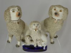 A pair of white ceramic figures of spaniels together with a similar smaller one with her puppies (