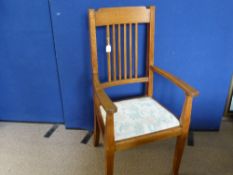 An Oak Spindle back Armchair having tapered front legs and floral fabric to the seat.