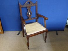 A Stained Oak Arm Chair having pierced decoration to back and top, patterned fabric to the seat.