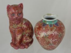 An oriental ceramic figure in the form of a cat decorated with flora and fauna on a pink ground