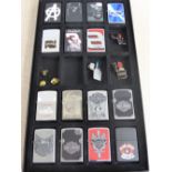 A Collection of Fifteen Zippo Lighters, in a glass covered collectors display case. Included amongst