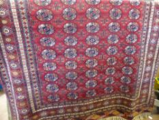 A Vintage Woollen Teke Style Rug, having red background with rows of guls within a central panel,