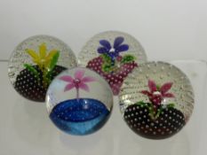 Four Caithness Glass Paper Weights, including 'Flower in the Rain' in red, blue, yellow and pink.