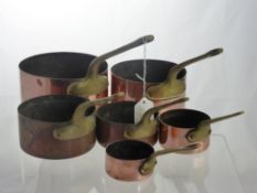 Six Graduated Copper Saucepans, with brass handles.