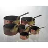 Six Graduated Copper Saucepans, with brass handles.
